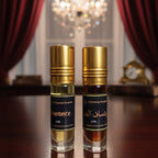 Two perfume bottles on a wooden surface with a chandelier in the background